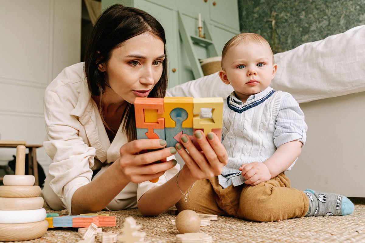 Een volwassene toont een baby een houten puzzelspeeltje